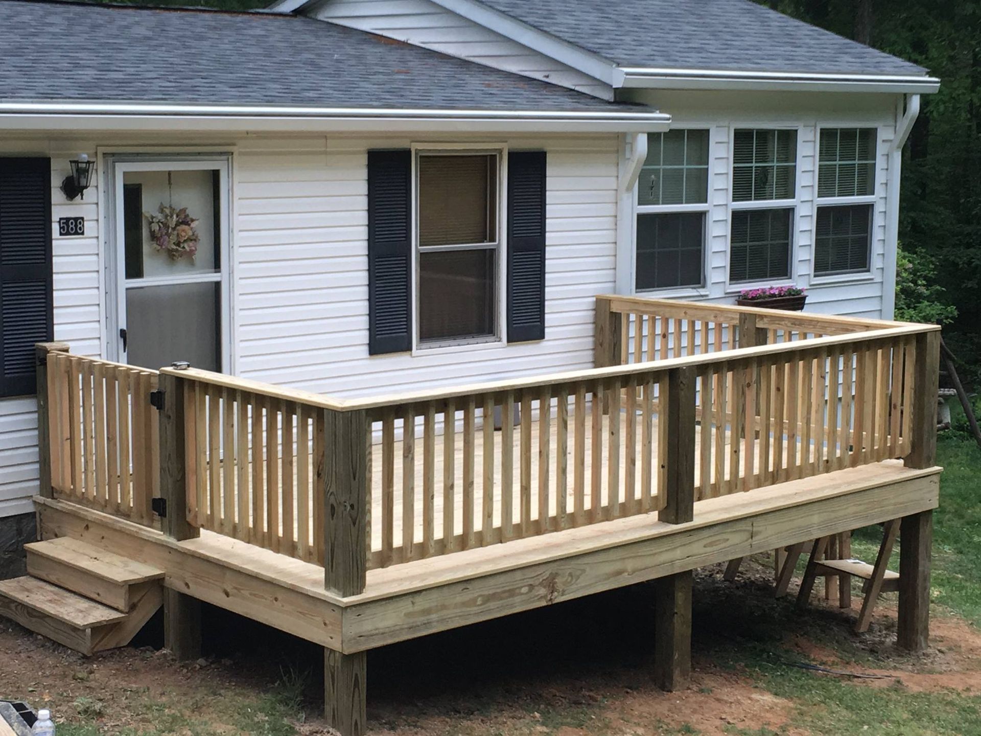 A white house with a wooden deck in front of it.