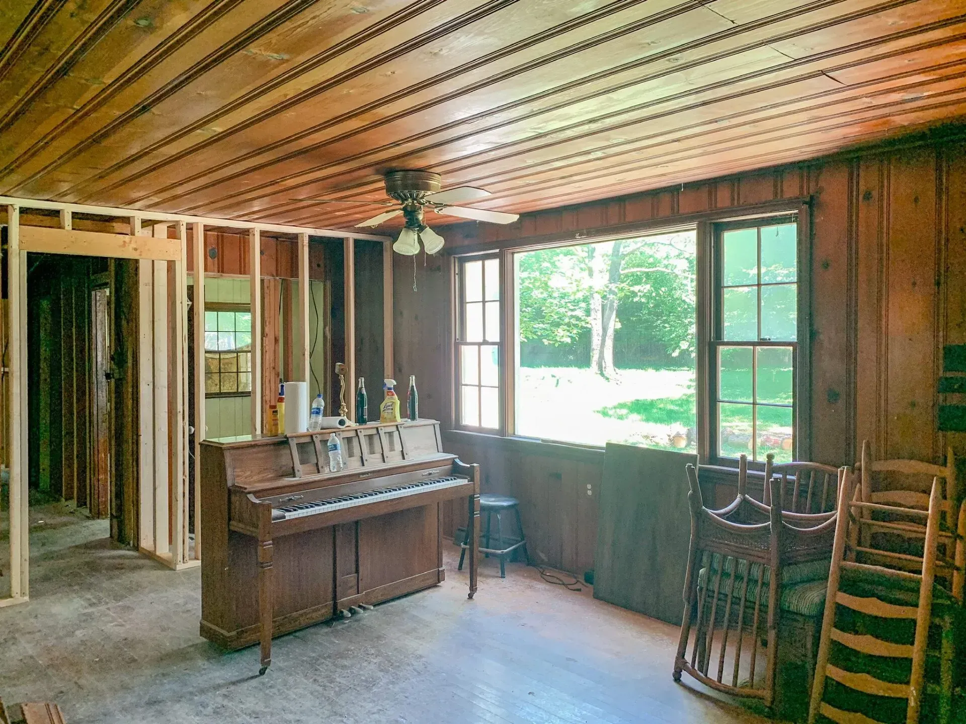 A living room with a piano and rocking chairs in it.