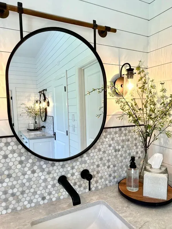 A bathroom with a round mirror and a sink.