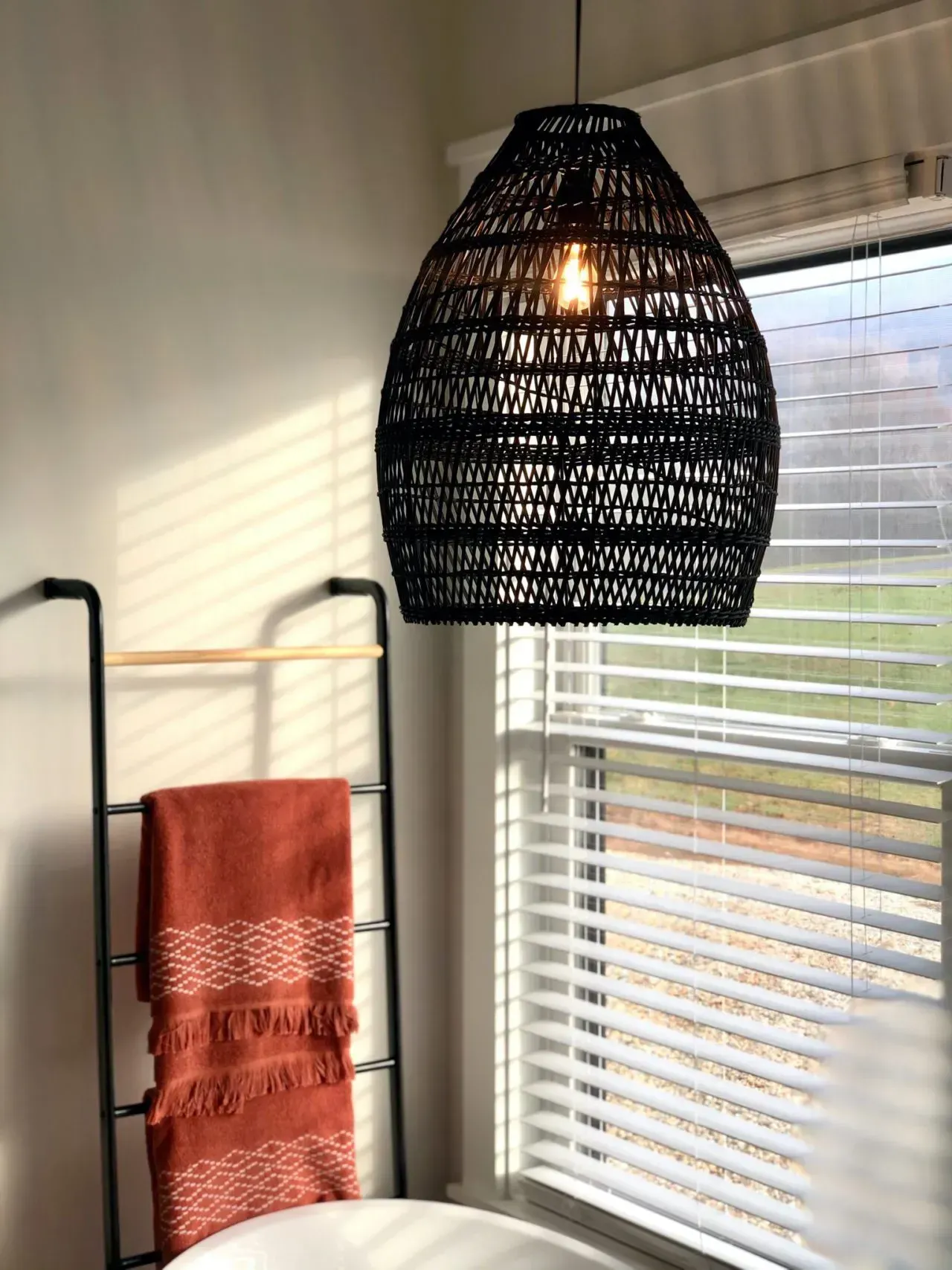 There is a lamp hanging from the ceiling in a bedroom next to a window.