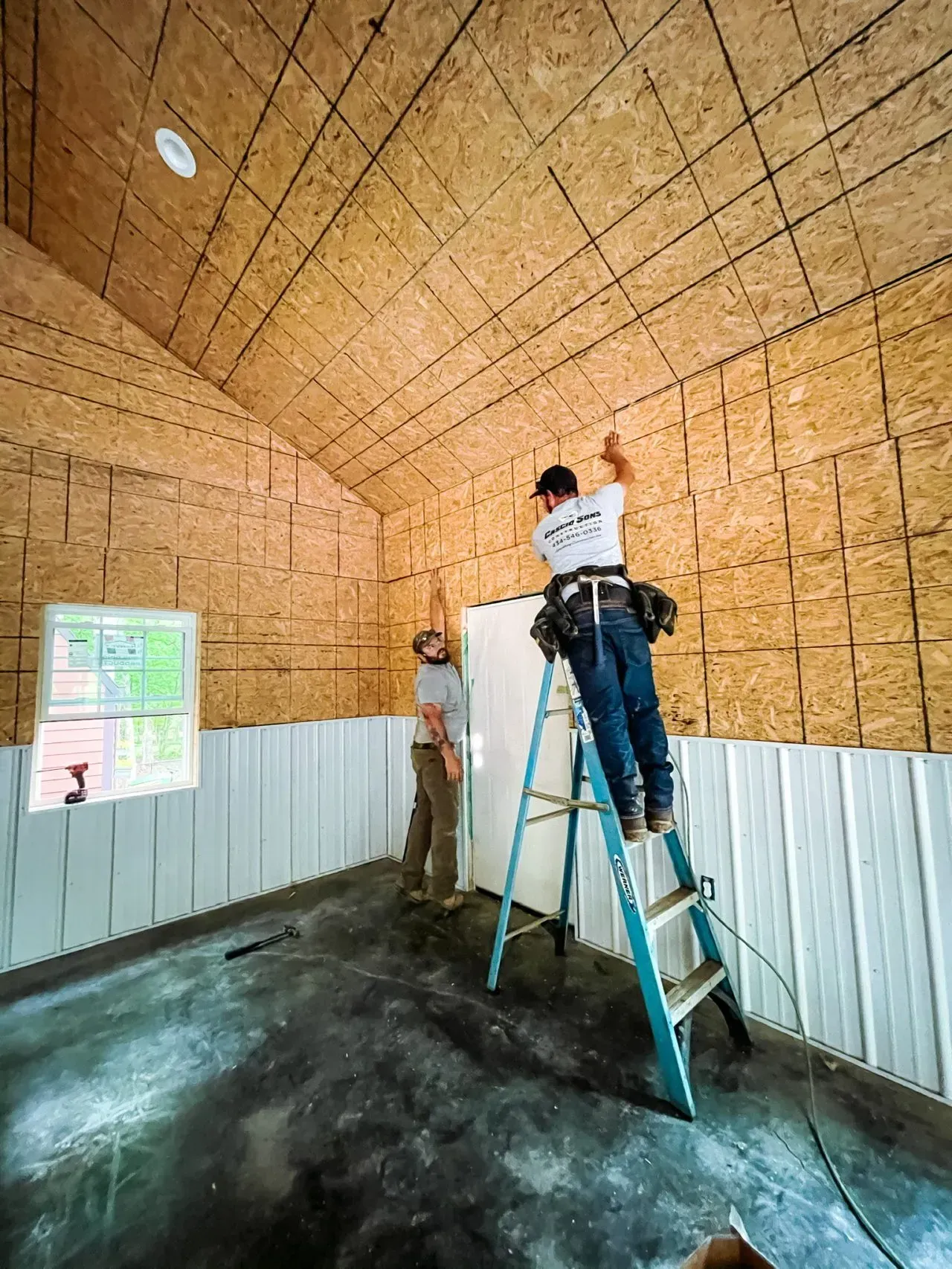 A man is standing on a ladder in a room.