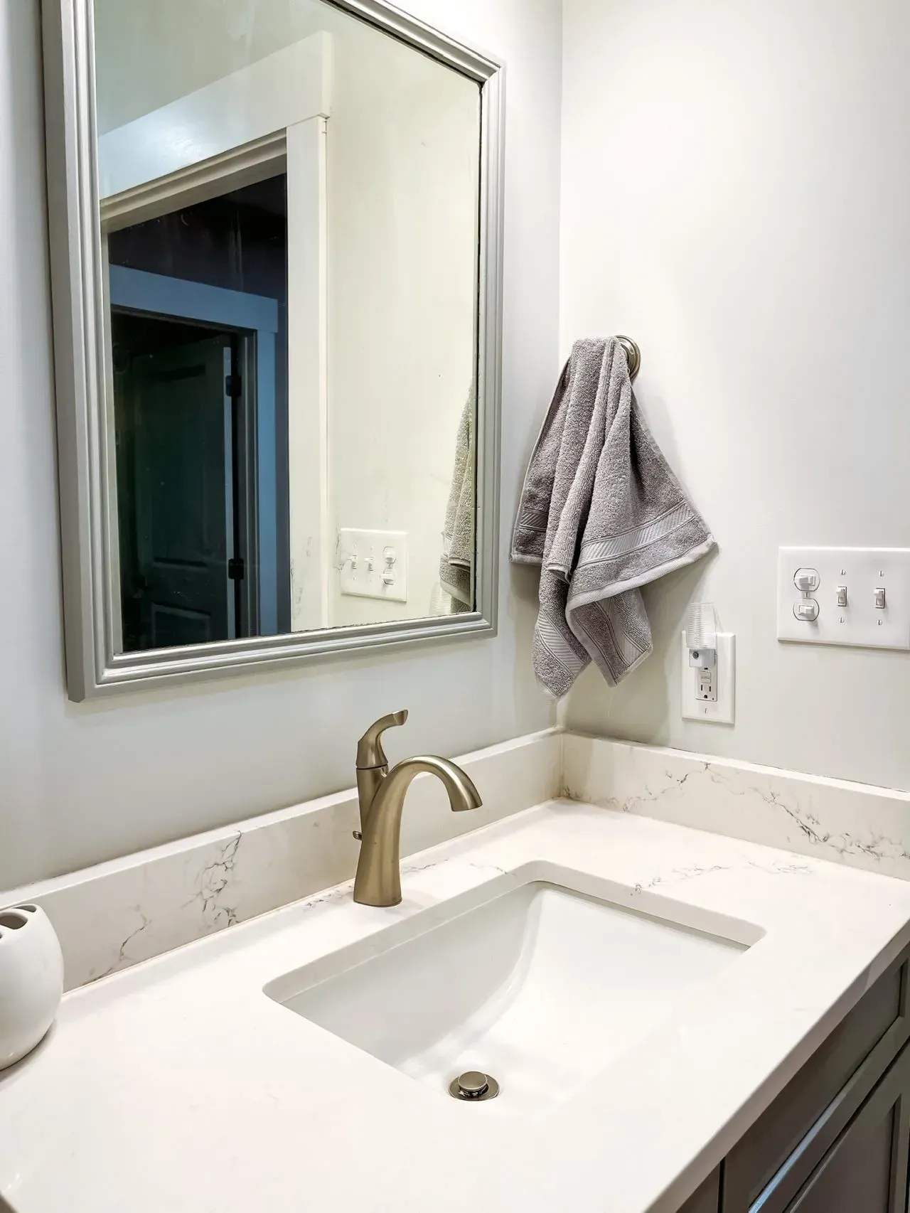 A bathroom with a sink , mirror and towel hanging on the wall.