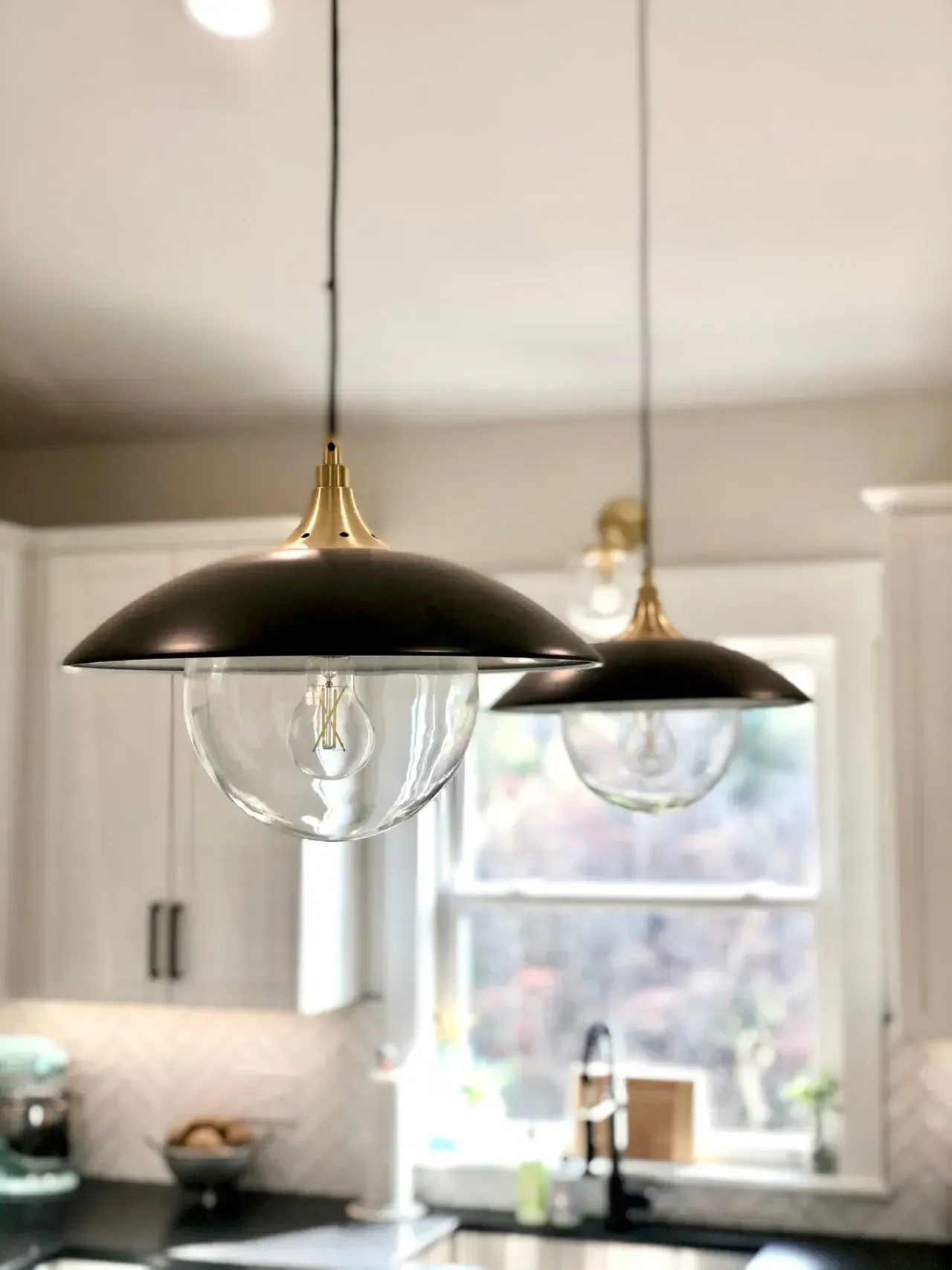 Two pendant lights are hanging from the ceiling in a kitchen.