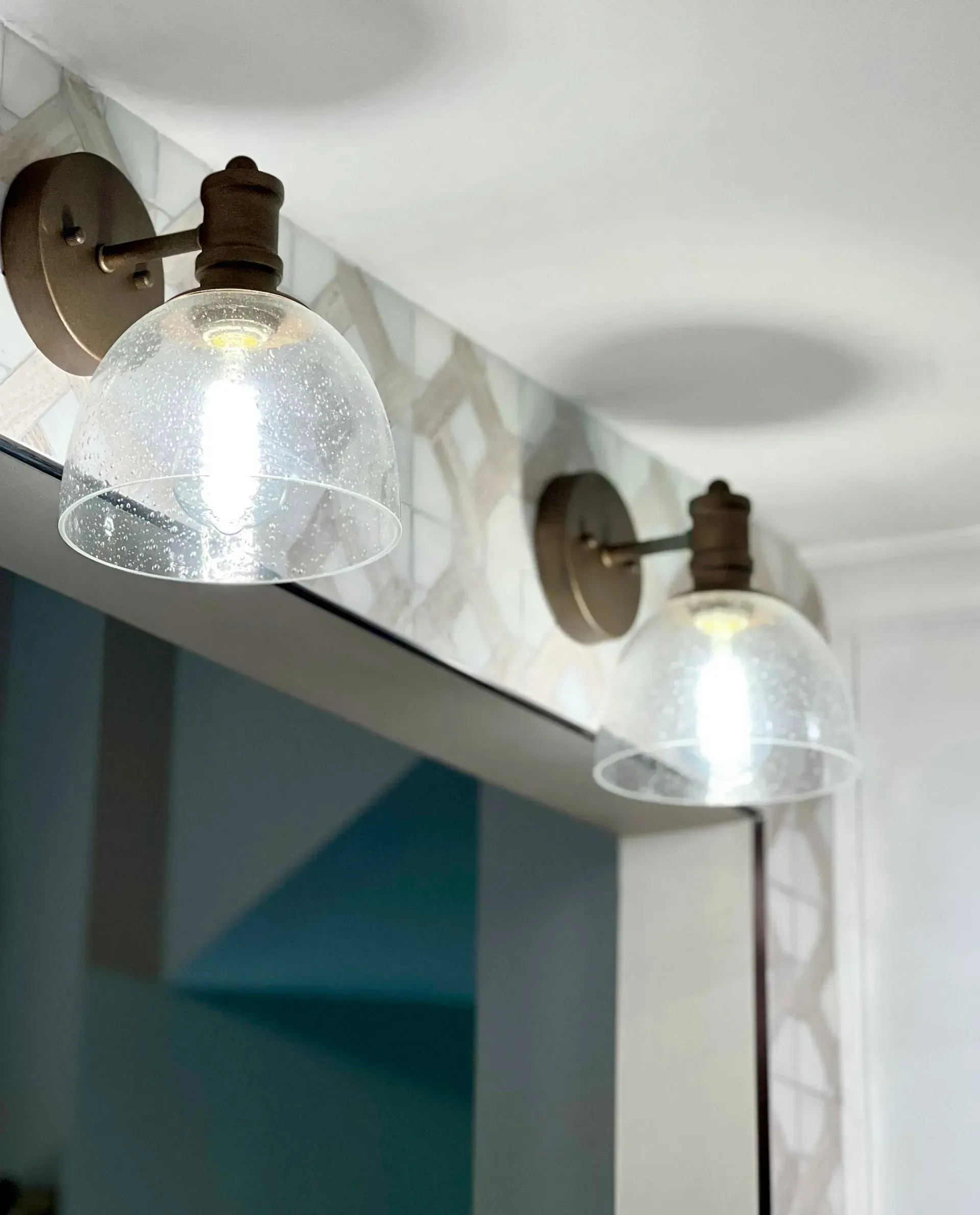 A bathroom mirror with two lights hanging from the ceiling