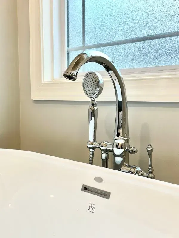 A bathtub with a faucet and a shower head next to a window.
