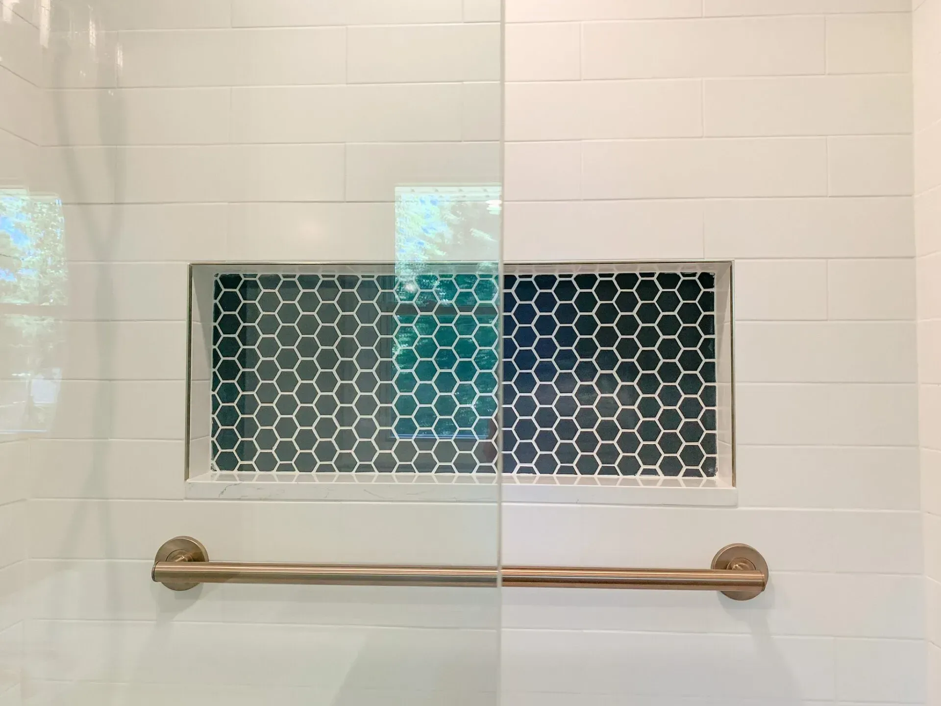 A shower stall with a shelf and a towel bar.