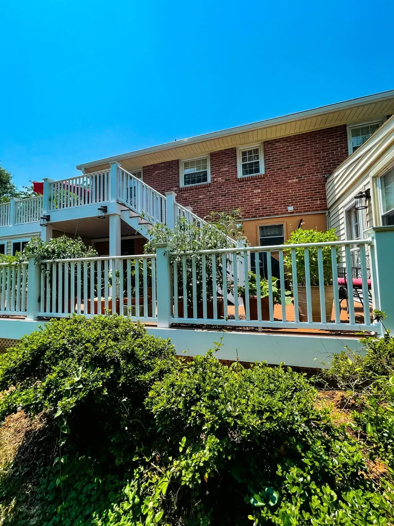 A large brick house with a white deck and stairs