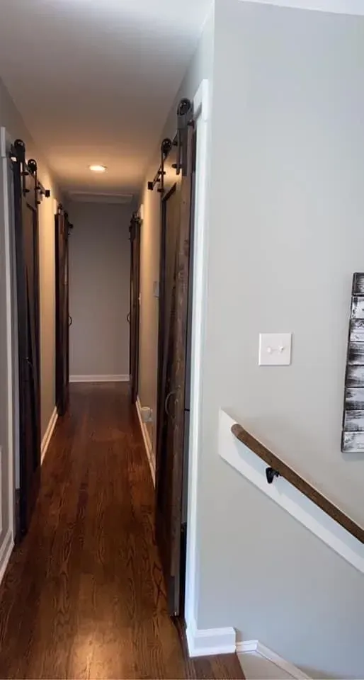 A hallway with sliding barn doors and stairs in a house.