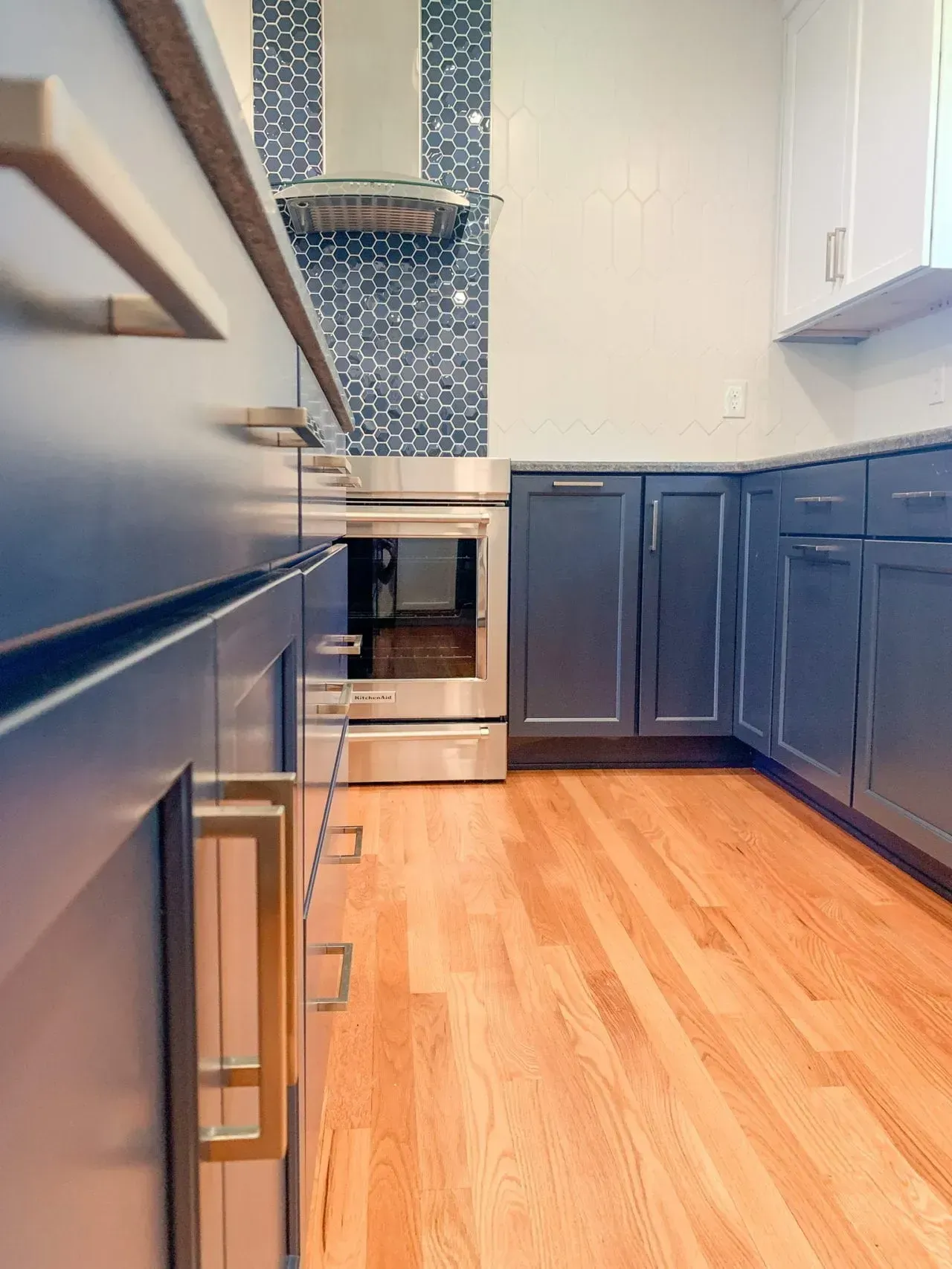 A kitchen with blue cabinets , stainless steel appliances , and hardwood floors.