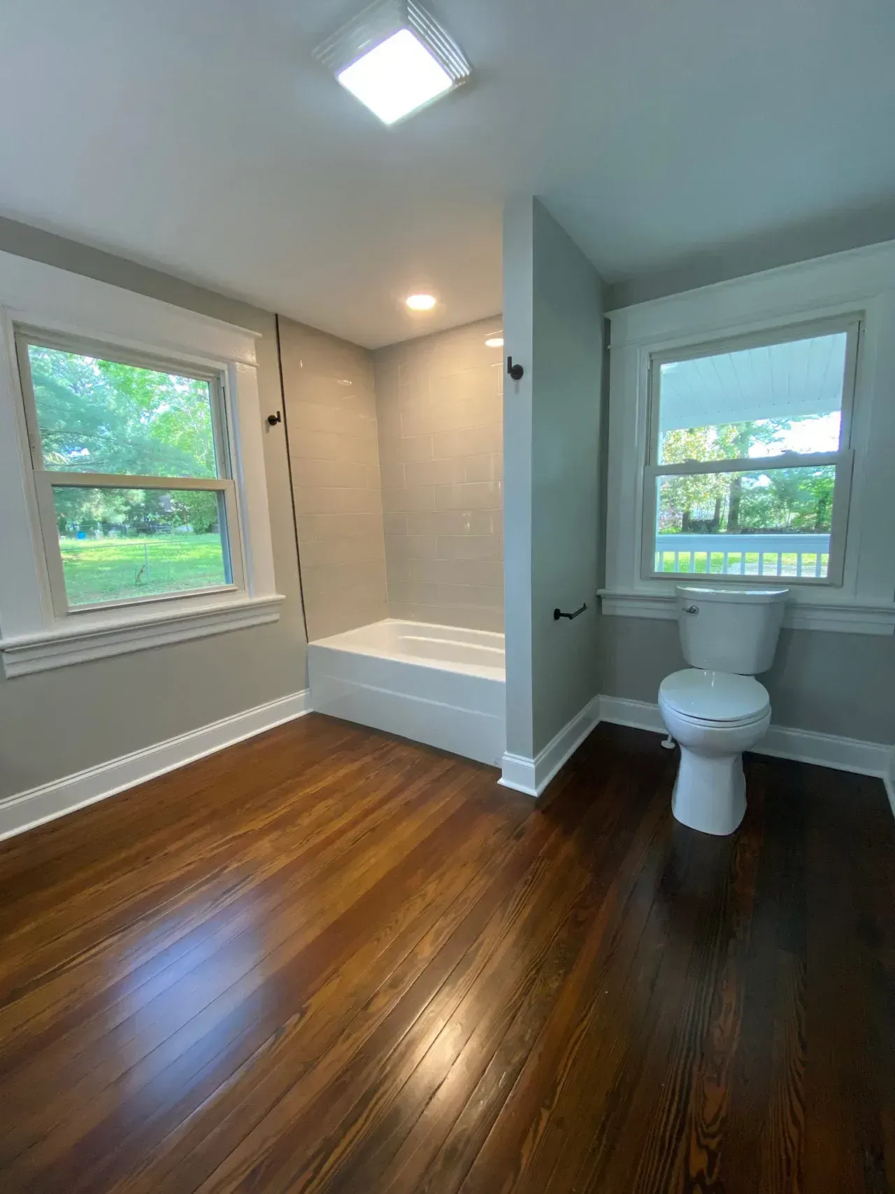 A bathroom with a toilet , tub , and window.