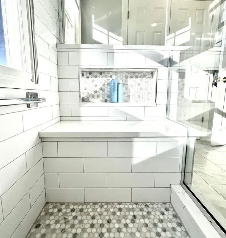 A bathroom with white tiles and a walk in shower.