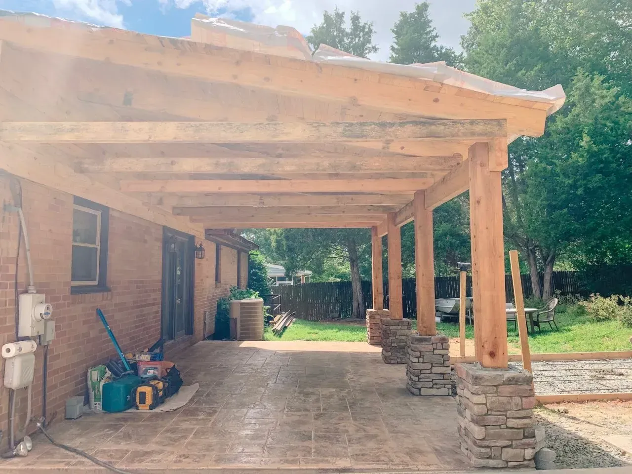 A wooden porch is being built on the side of a brick house.