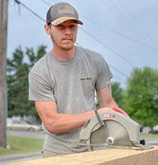 A man is using a circular saw to cut a piece of wood.