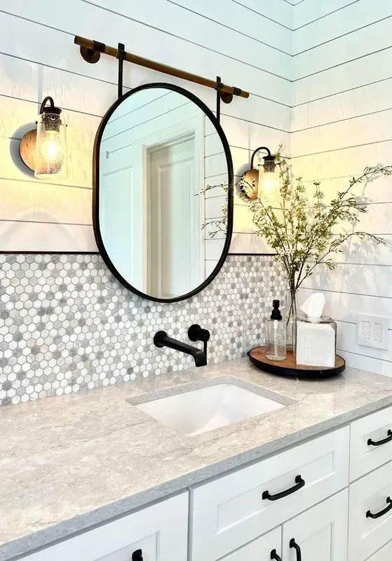 A bathroom with a sink , mirror , and light fixtures.