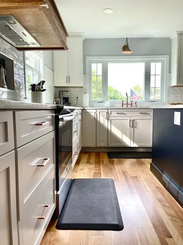 A kitchen with white cabinets and a black rug on the floor.