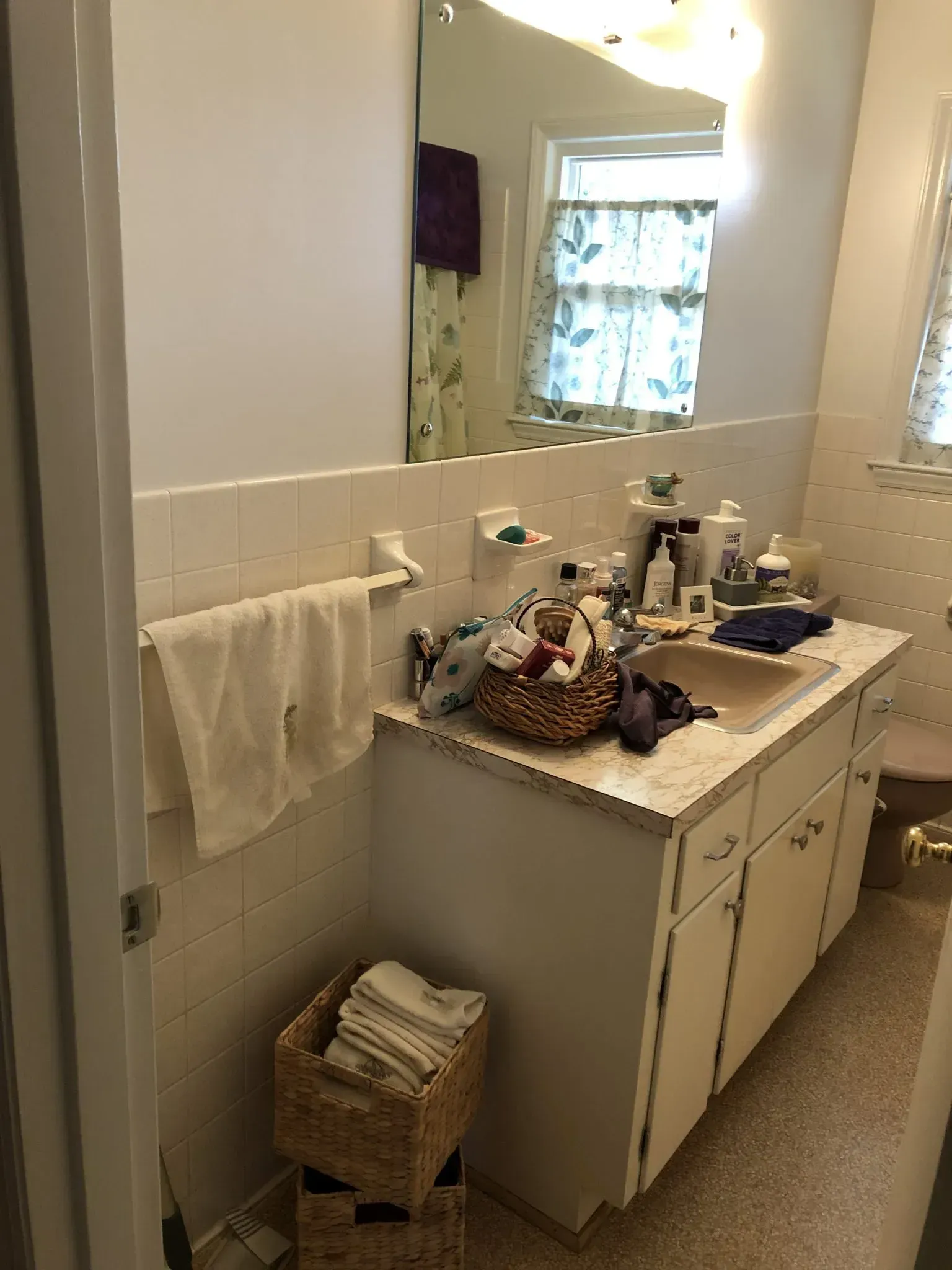 A bathroom with a sink , mirror and towels on the counter.