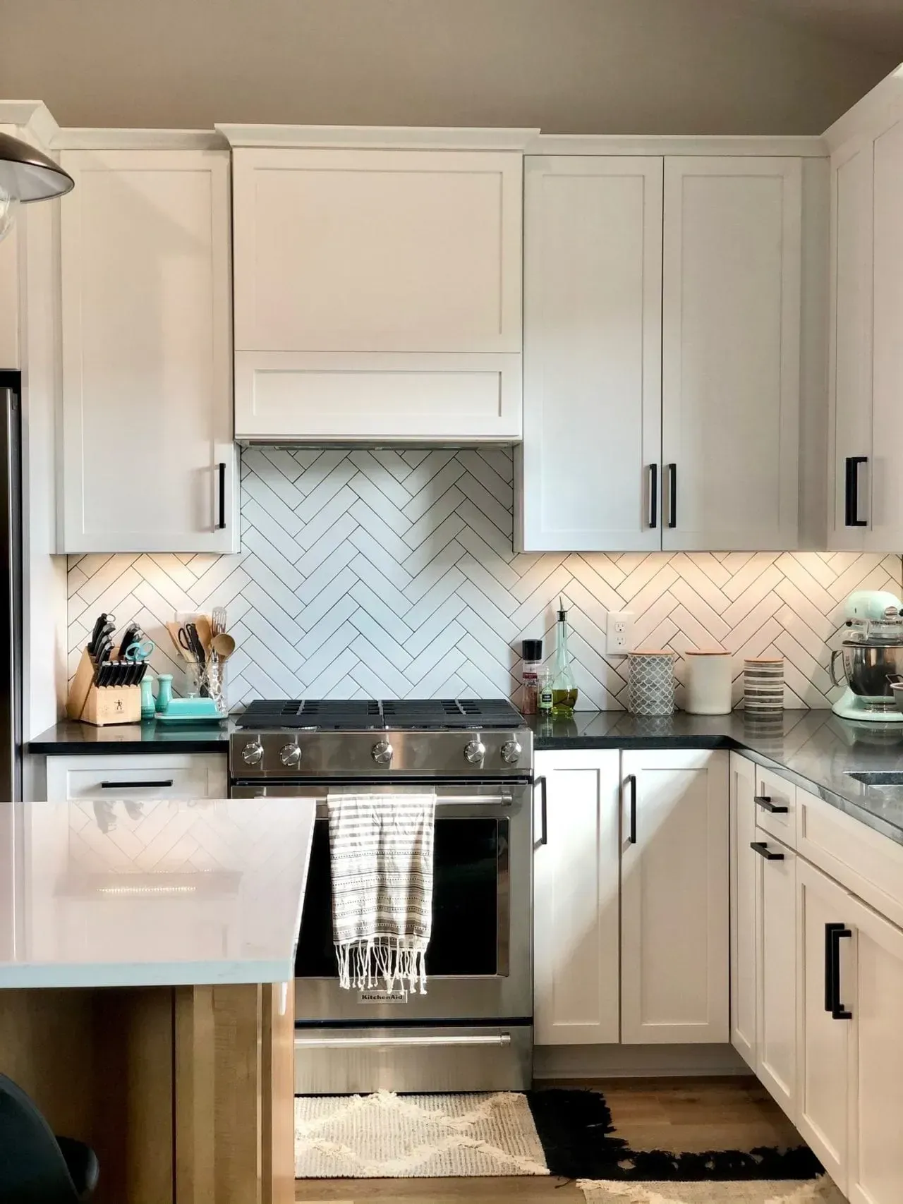 A kitchen with white cabinets , stainless steel appliances , a stove and a sink.