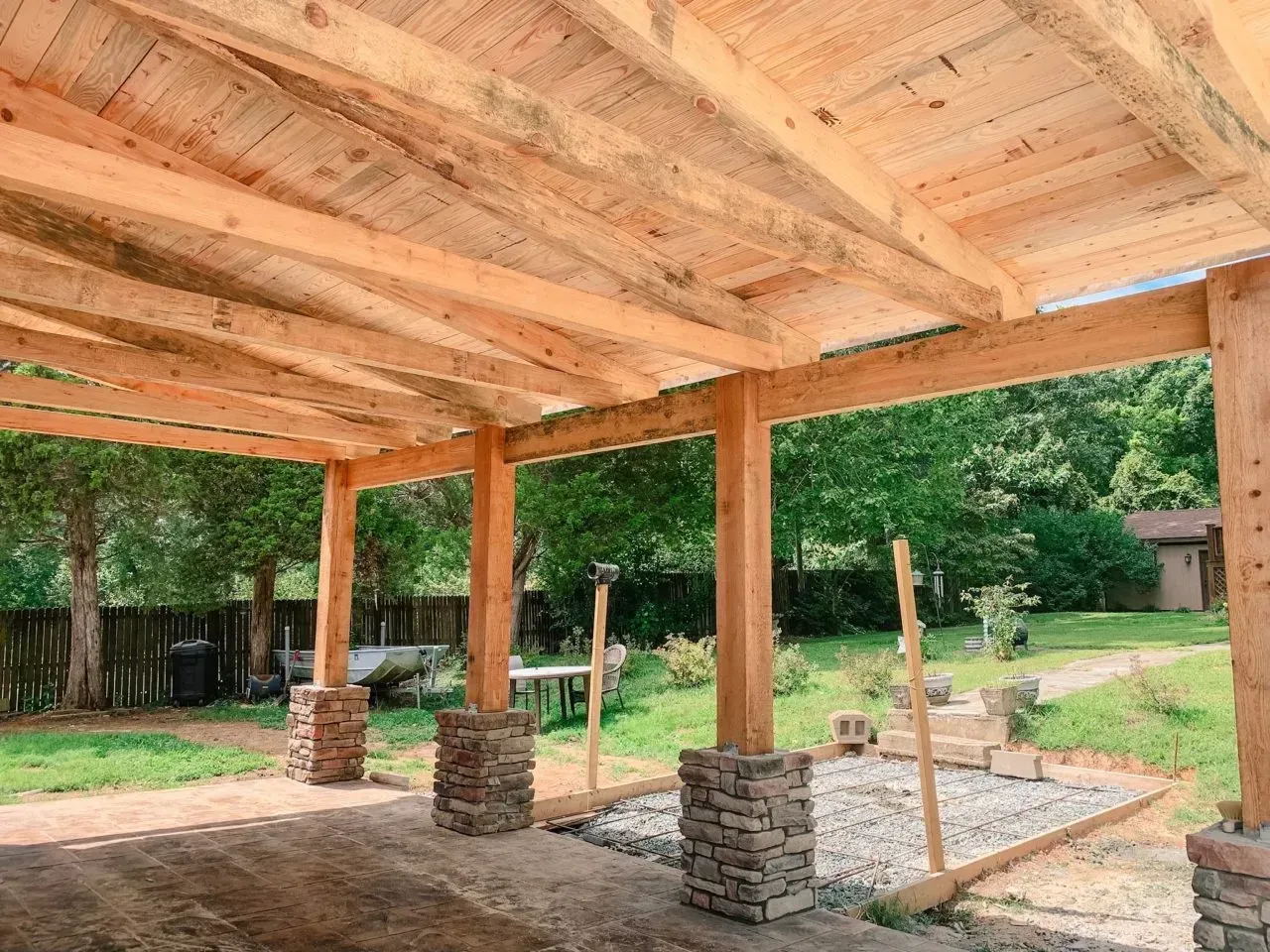 A wooden pergola is being built in a backyard.