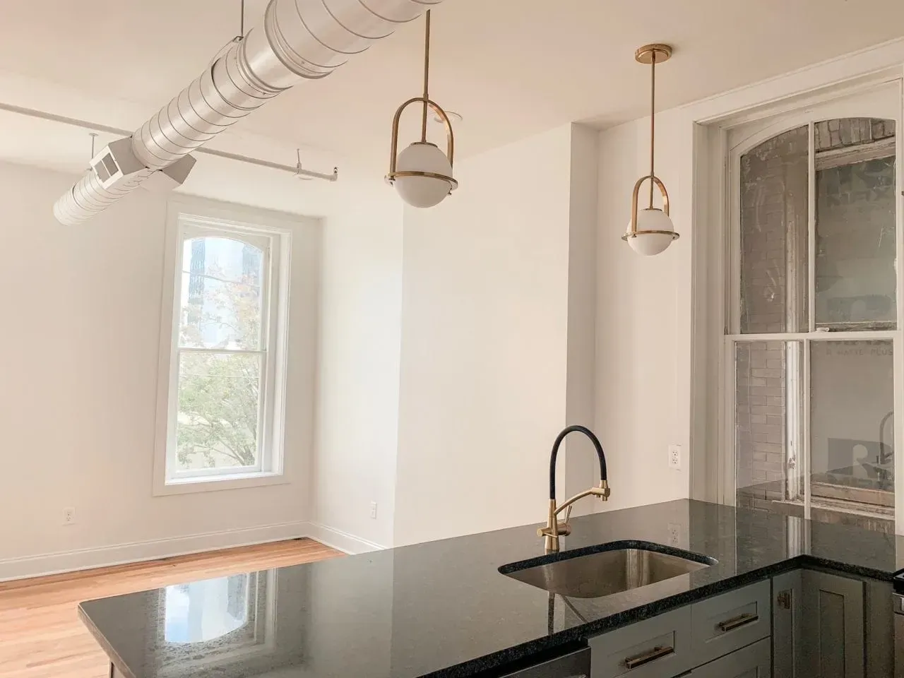 An empty kitchen with a sink and a window.
