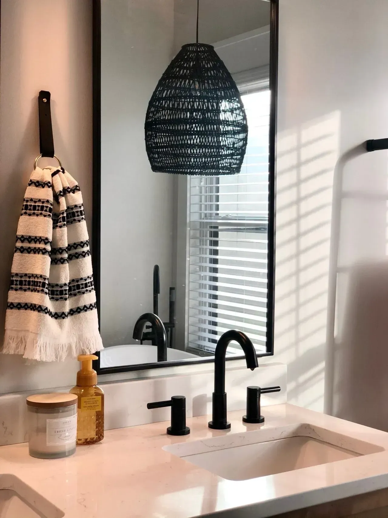 A bathroom with a sink , mirror and towel hanging on the wall.