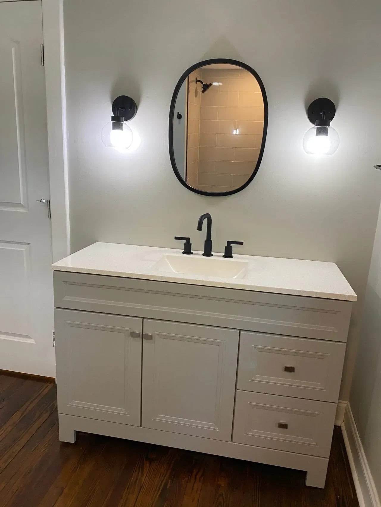 A bathroom with a white vanity , sink and mirror.