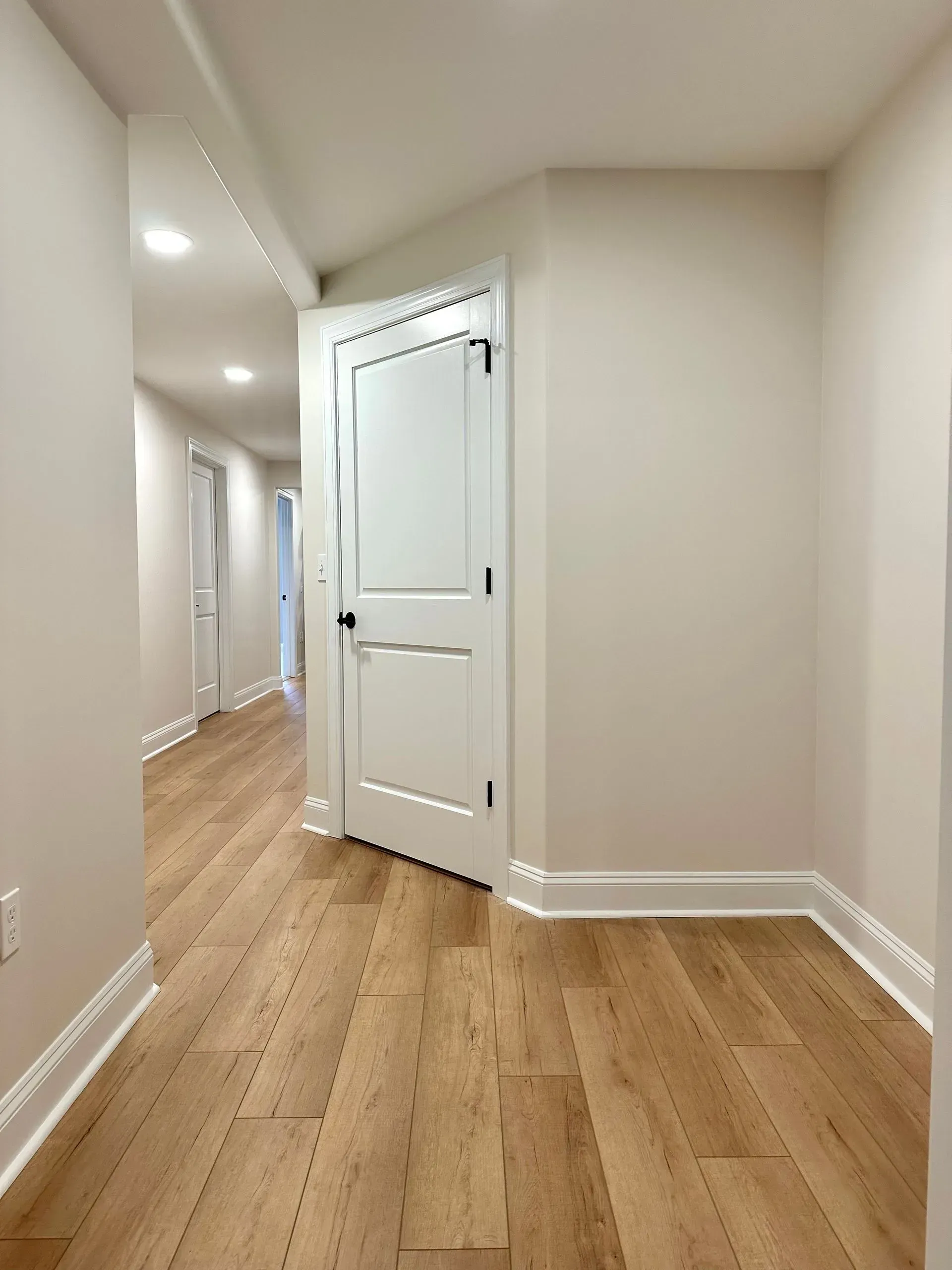 A long hallway with hardwood floors and white walls.