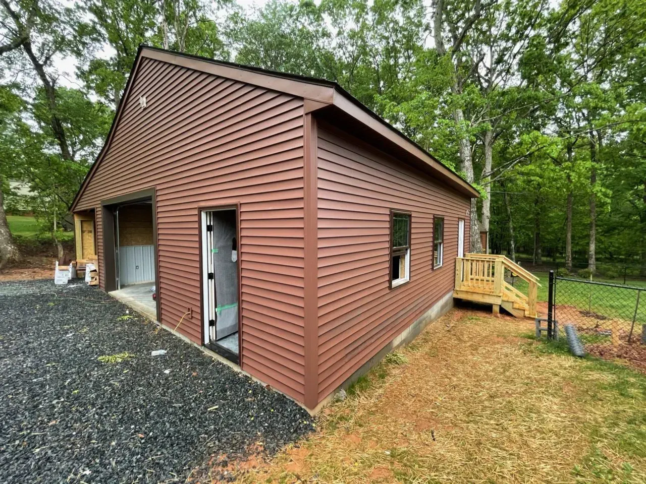 A brown garage with a wooden deck in the backyard.