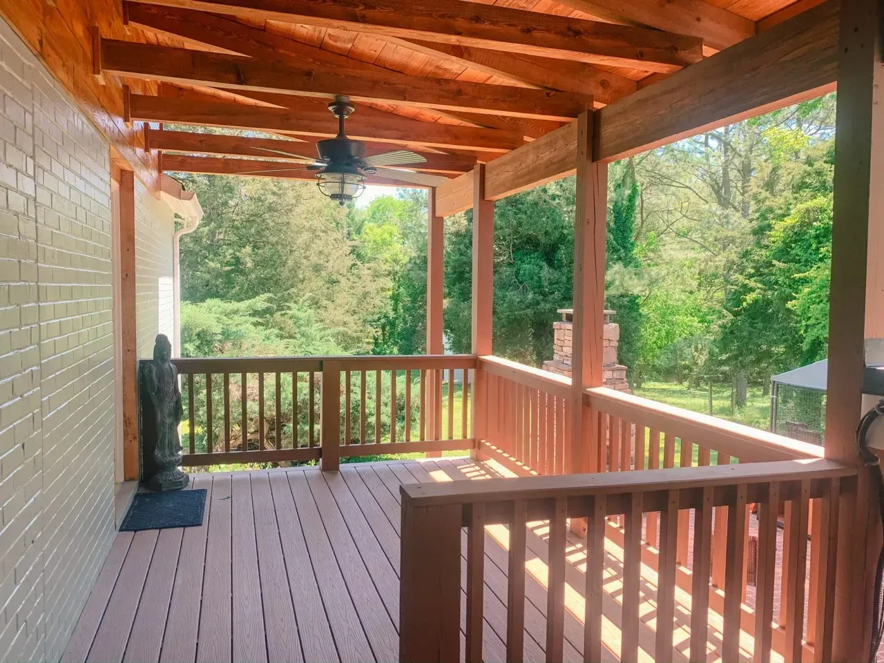 A porch with a ceiling fan and a view of the woods.