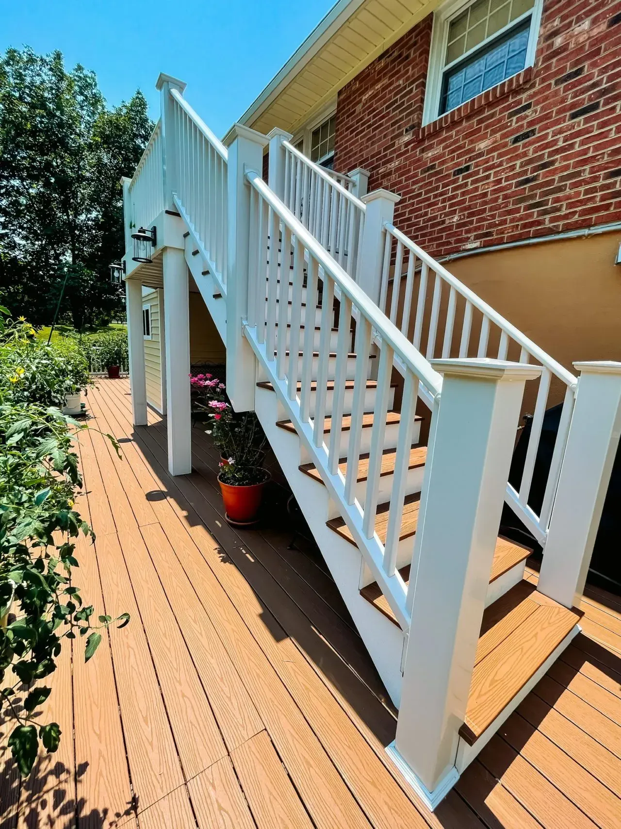 A wooden deck with white stairs leading up to a brick house.