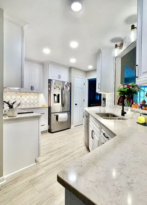A kitchen with white cabinets and a stainless steel refrigerator.