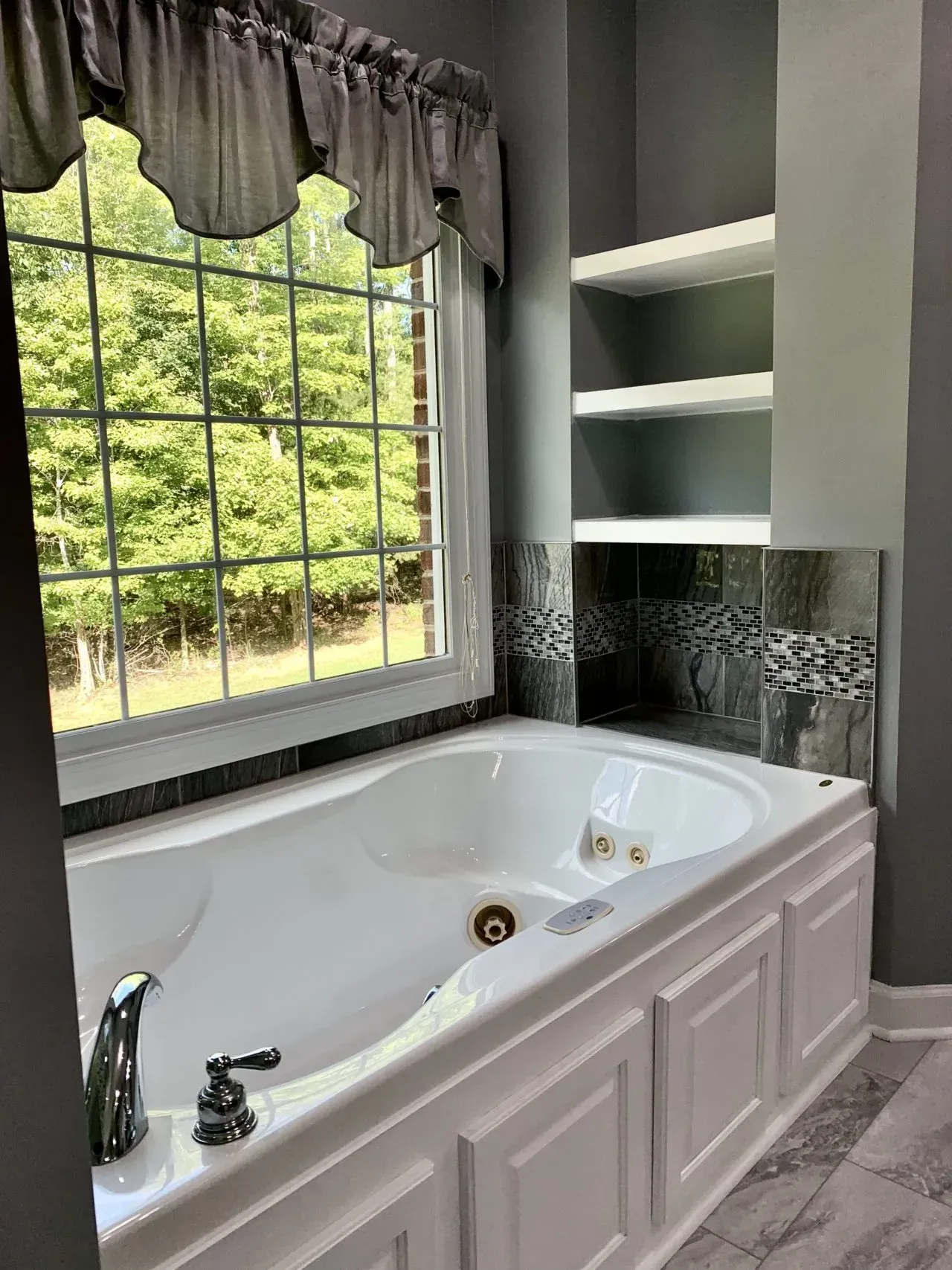 A bathroom with a jacuzzi tub and a window.