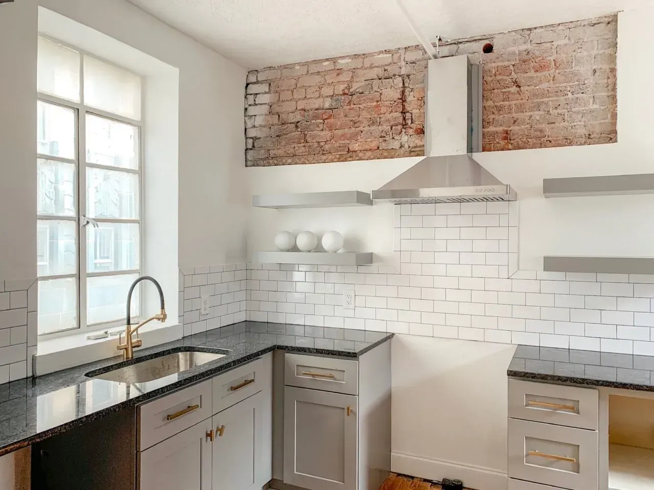 A kitchen with a sink and a brick wall