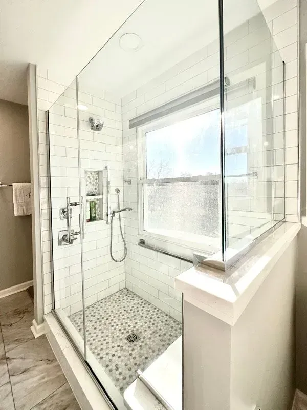 A bathroom with a walk in shower and a window.