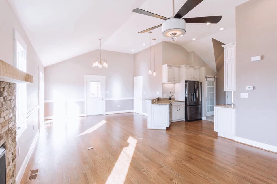 An empty living room with hardwood floors and a ceiling fan.