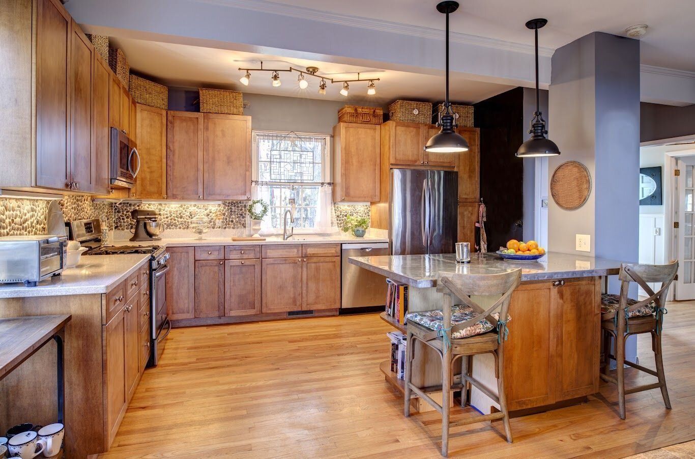 A kitchen with wooden cabinets , stainless steel appliances , and a large island.