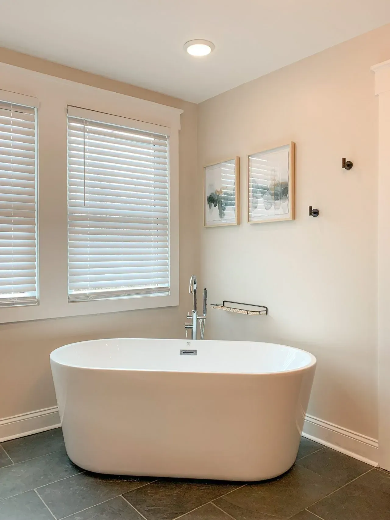 A bathroom with a bathtub and two windows.