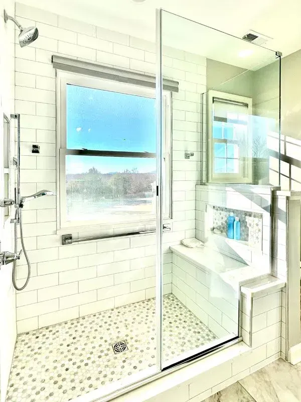A bathroom with a walk in shower and a window.