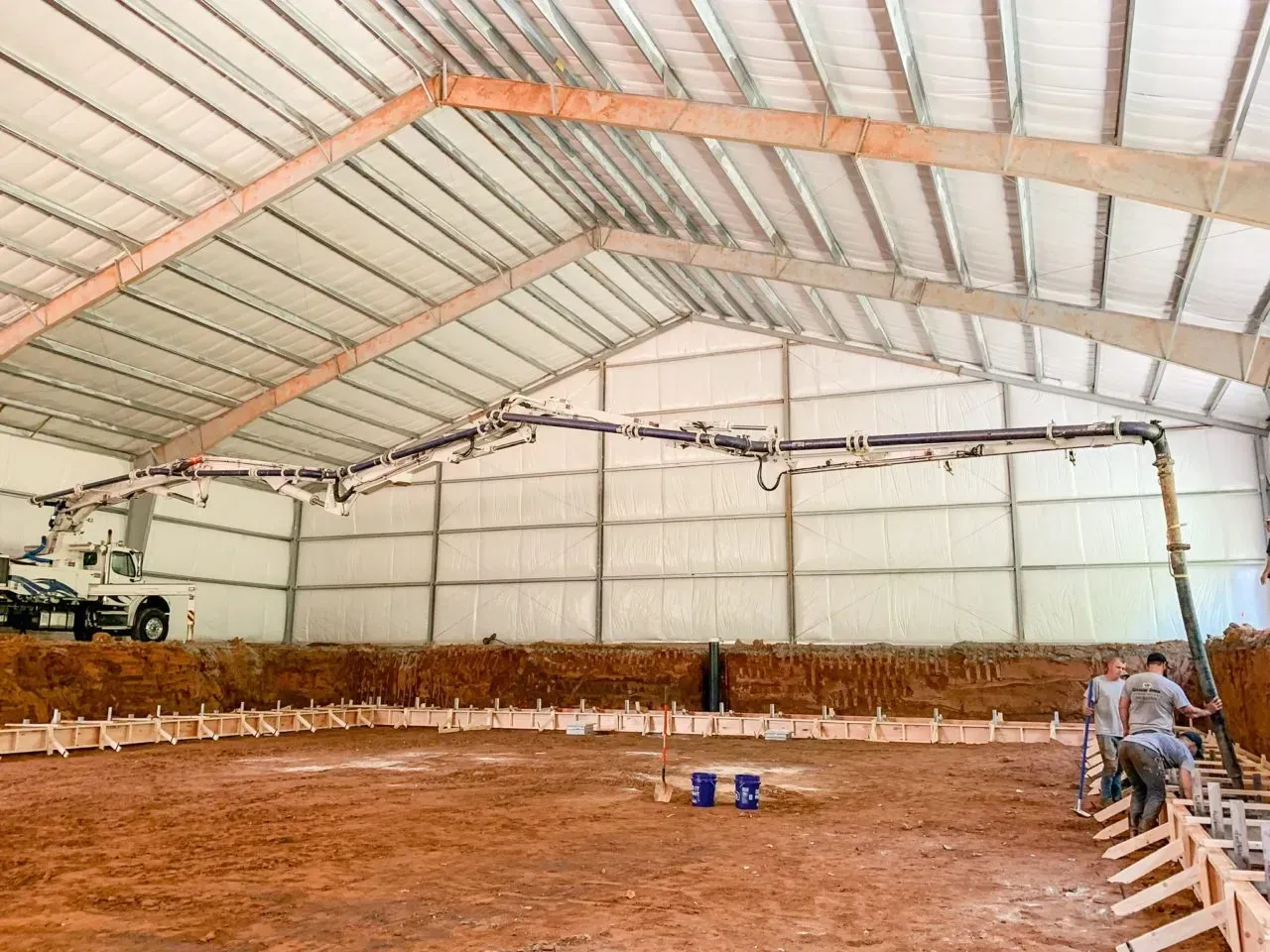 A concrete pump is being used to pour concrete into a large building.