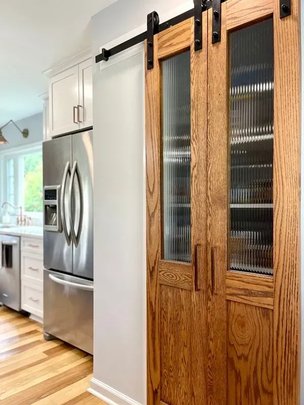 A kitchen with sliding barn doors and a stainless steel refrigerator