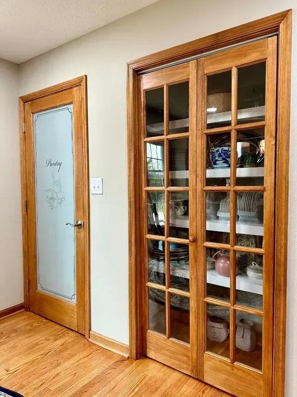 A kitchen with sliding glass doors and shelves filled with dishes.
