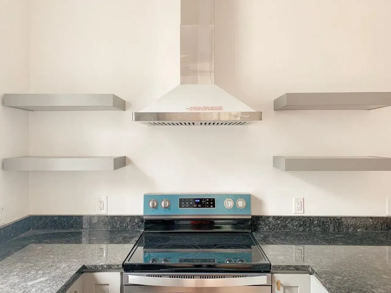 A kitchen with a stove and a hood above it.
