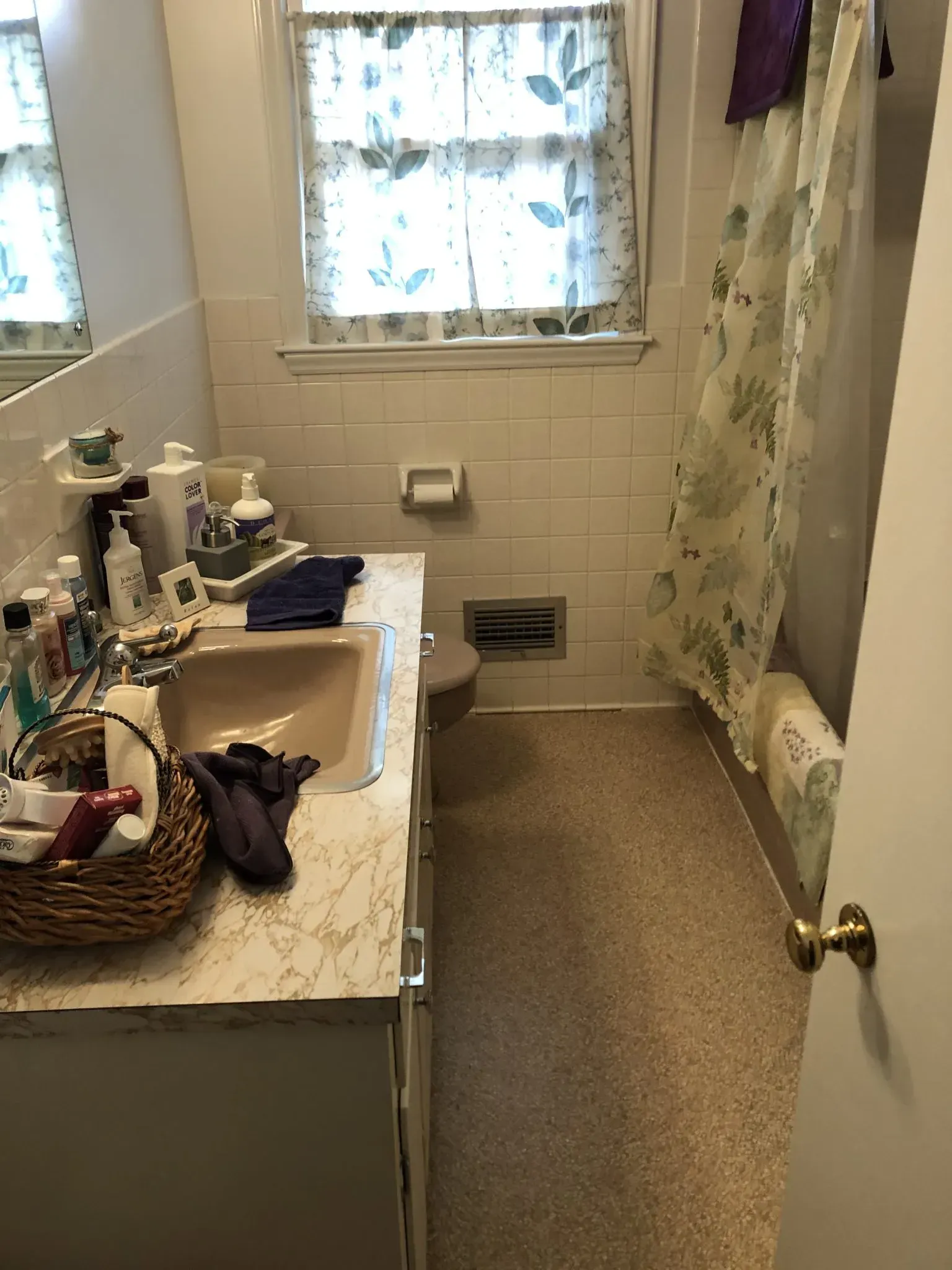 A bathroom with a sink , toilet , mirror and shower curtain.