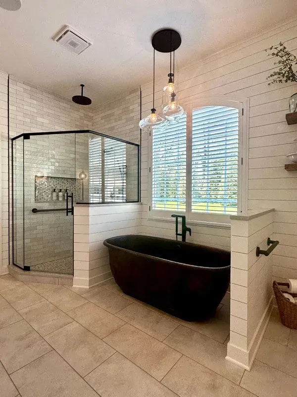 A bathroom with a black tub and a walk in shower.