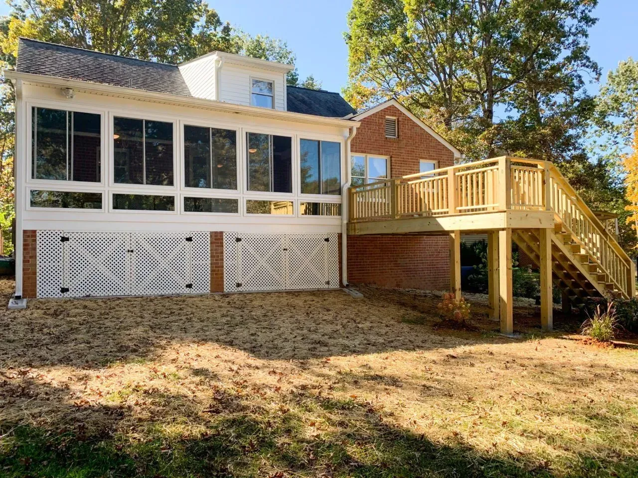 A house with a screened in porch and a wooden deck.