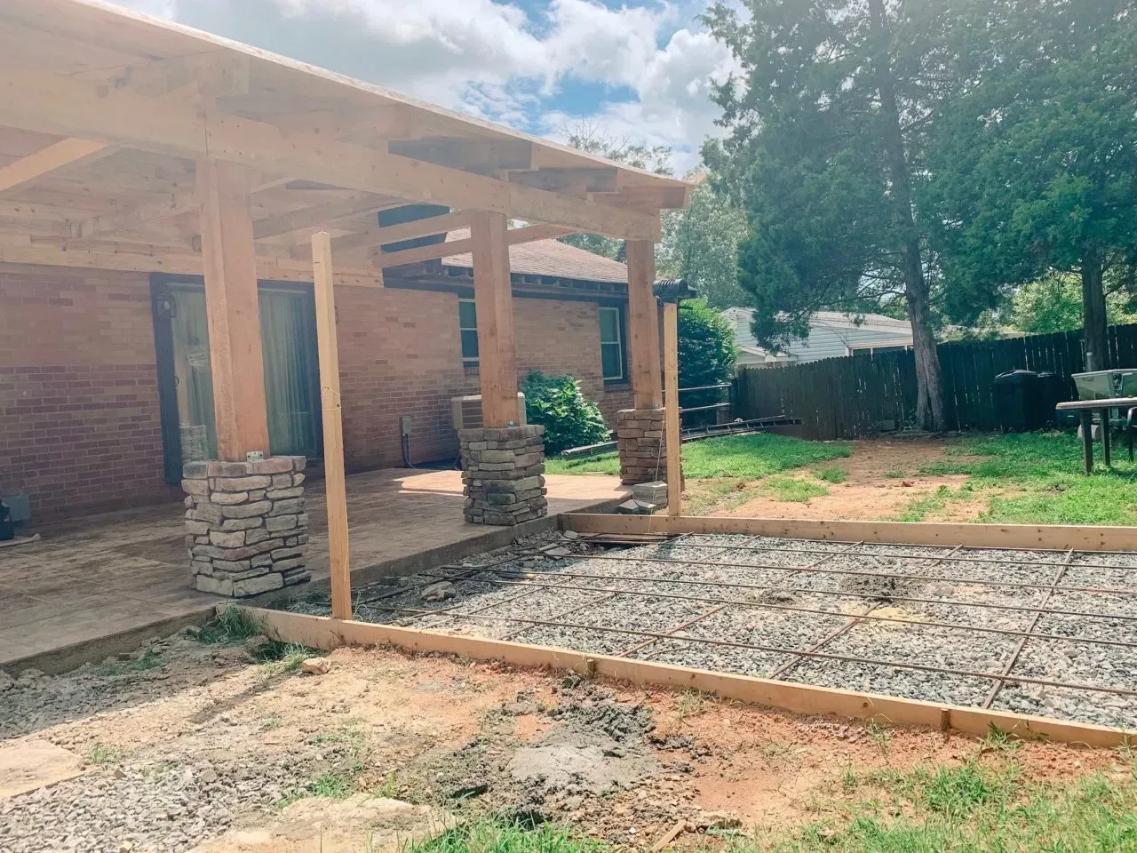 A wooden pergola is being built in the backyard of a house.