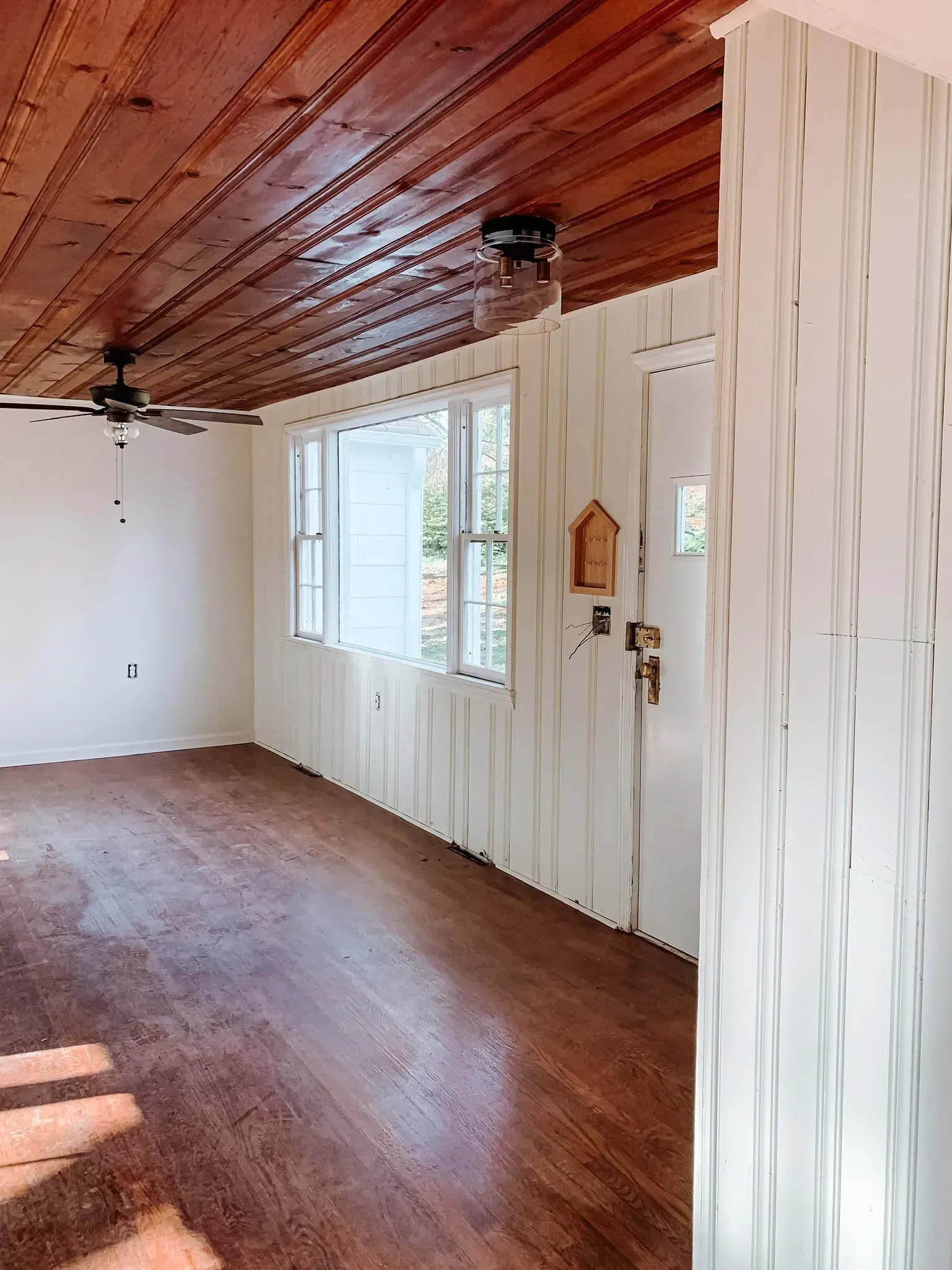A living room with a wooden ceiling and a ceiling fan.