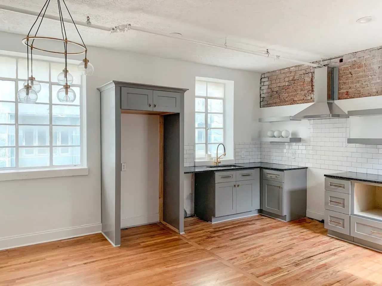 An empty kitchen with wooden floors and gray cabinets