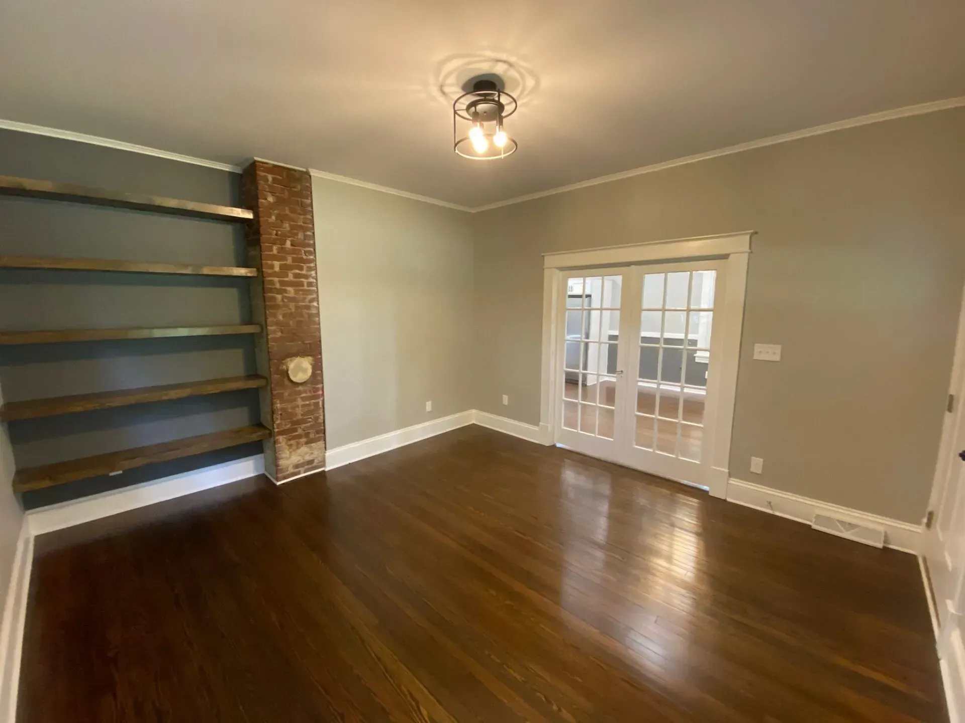 An empty living room with hardwood floors and french doors.