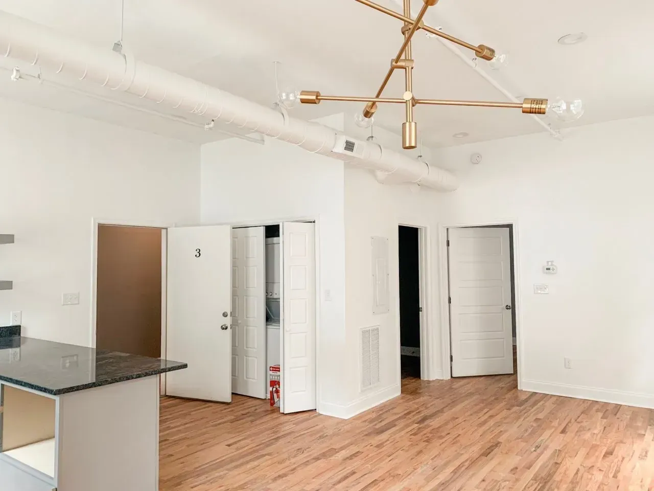 A large empty room with hardwood floors and white walls.