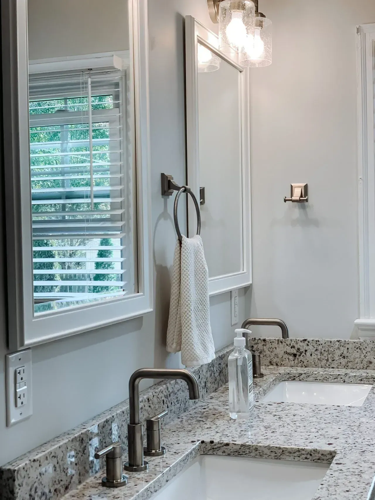 A bathroom with two sinks , a mirror and a window.